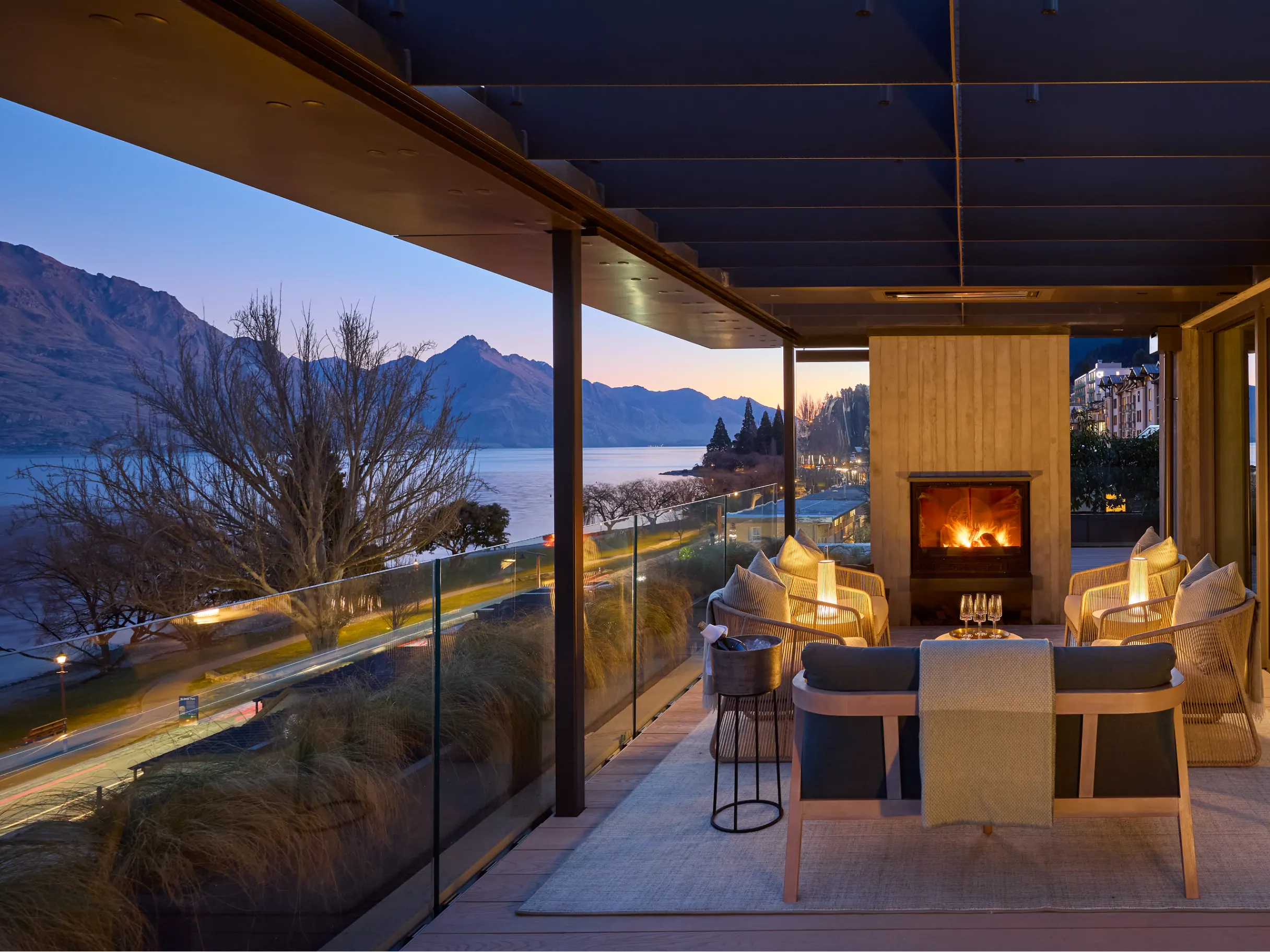 Stylish patio with a log fire overlooking mountains and lake at sunset