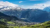 View across lush, sunny mountains with snowy peaks in the Swiss Alps