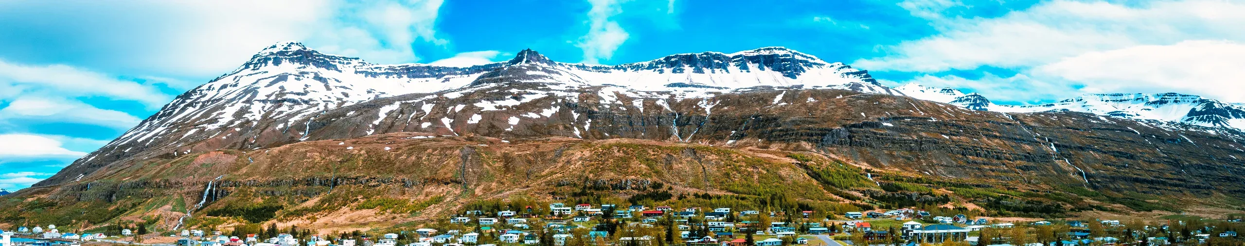 Stunning aerial view of a small town on an Icelandic peninsula surrounded by calm waters and snowy mountains