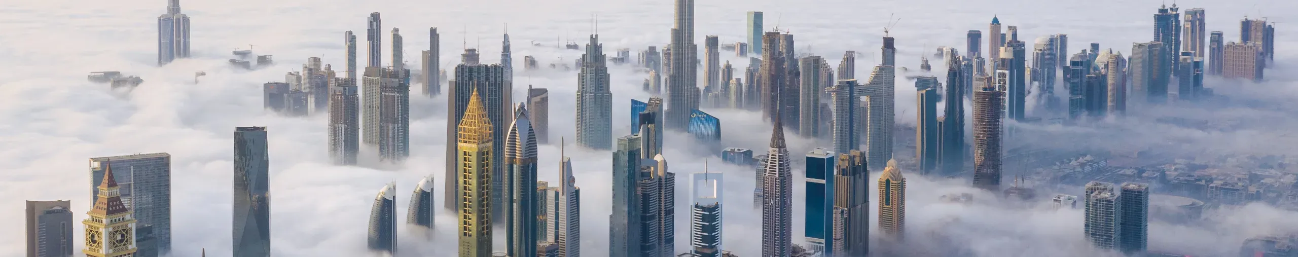 Arial view of Dubai skyline covered in dense fog. 