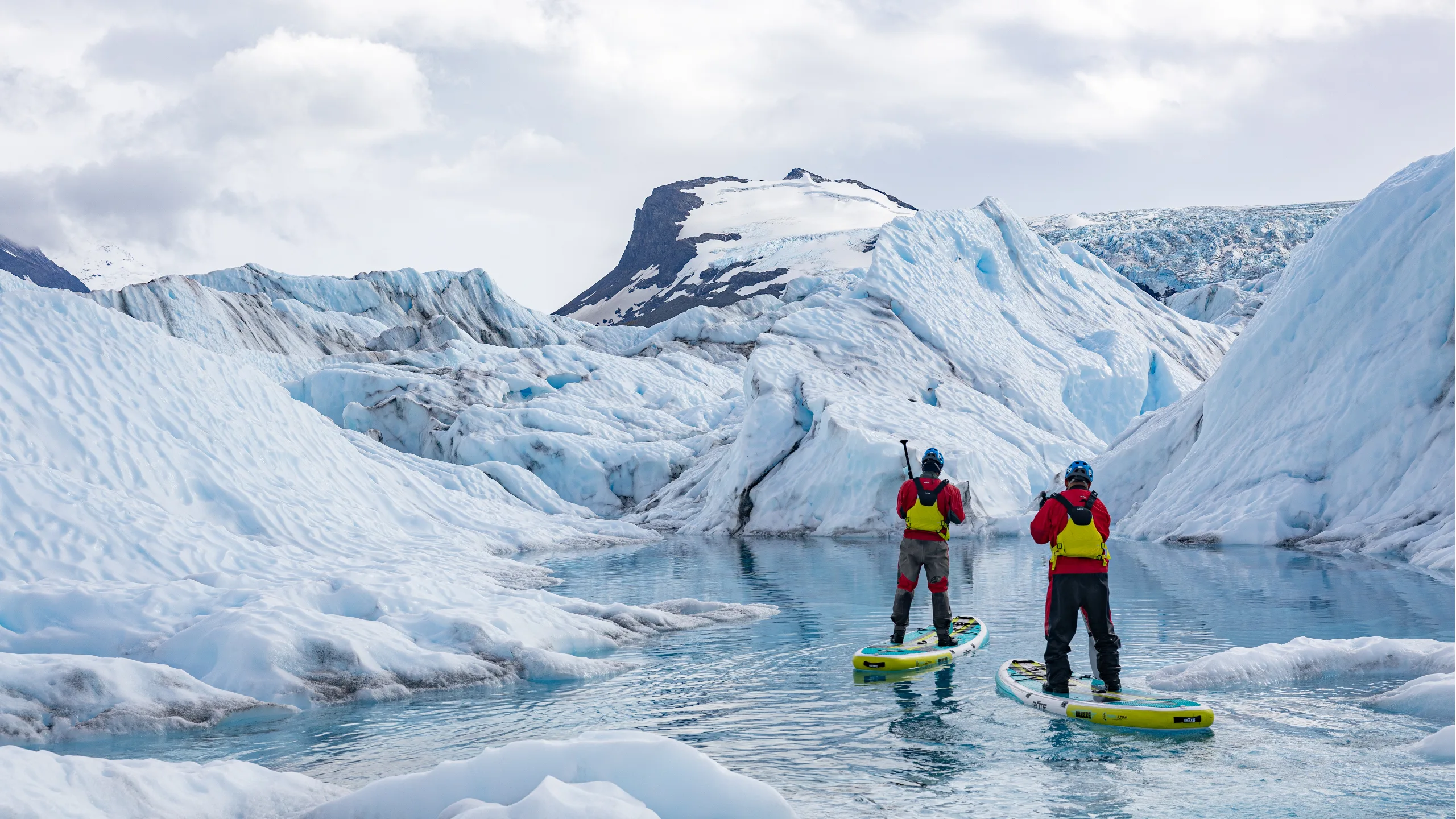 Two people paddleboarding in snowy Alaska