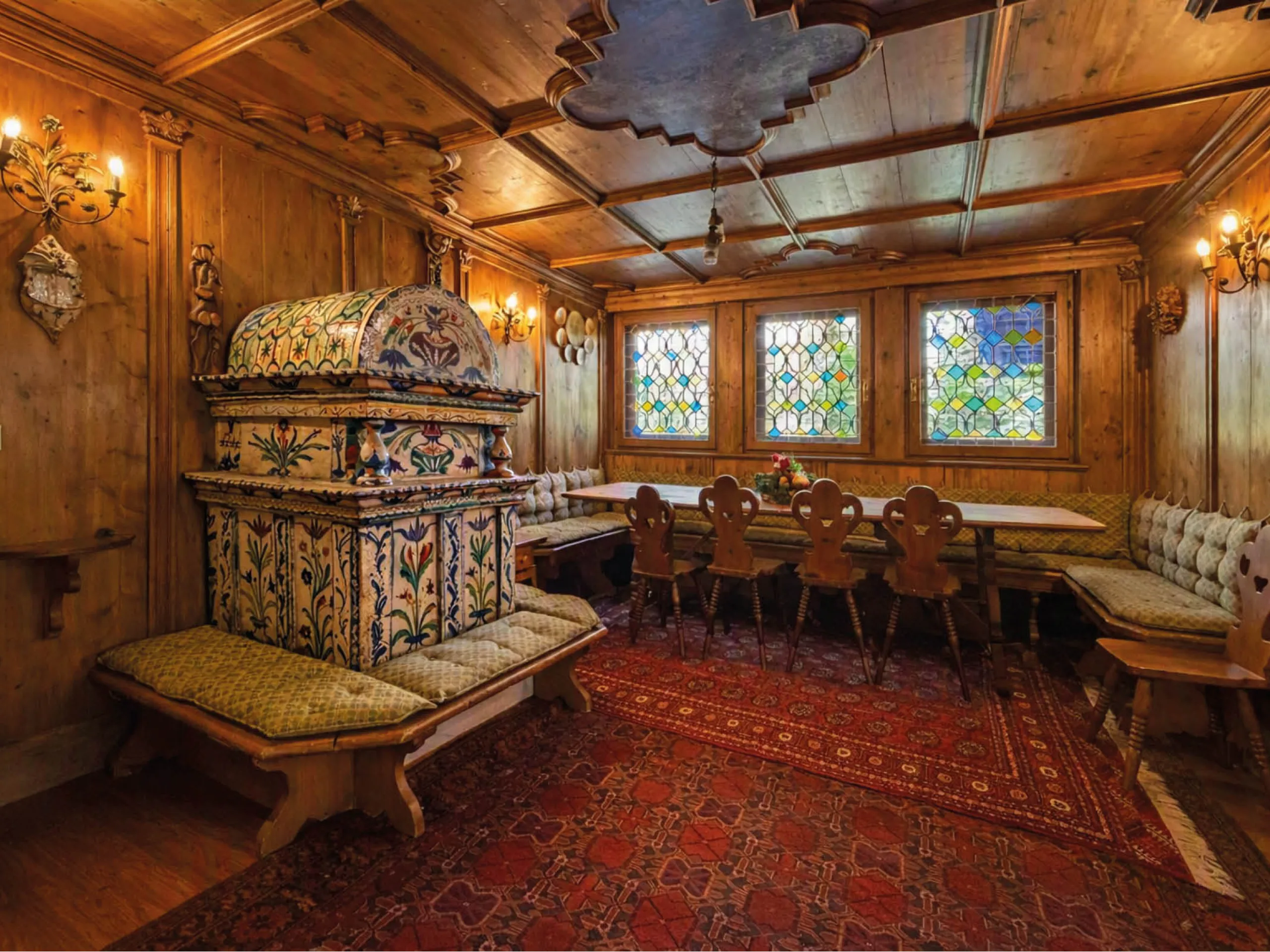 Plush interior of a chalet in Cortina d'Ampezzo, with red carpets and colourful stained glass windows