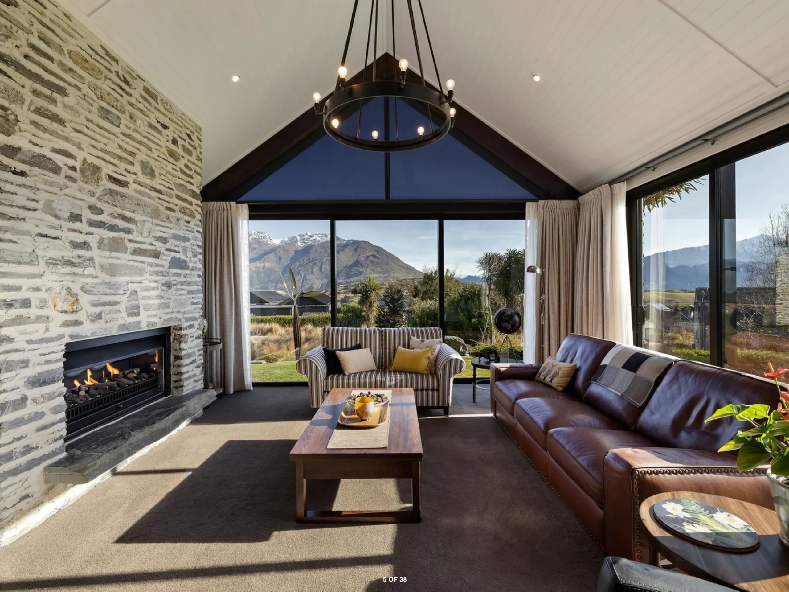 Modern, light-filled living room in Queenstown with a fireplace and mountain views beyond