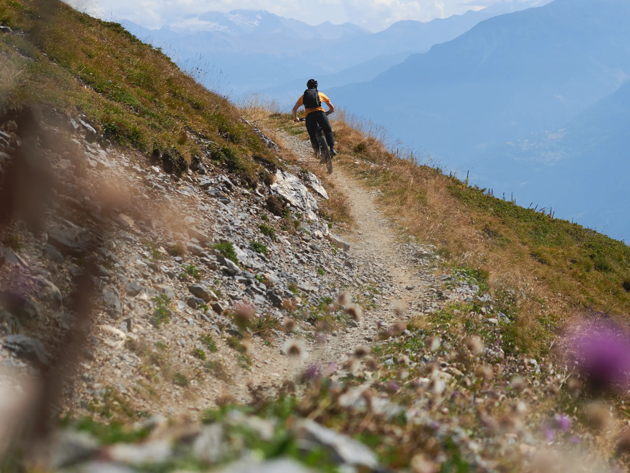 Mountain biker rides narrow trail on mountain ridge
